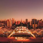 Vista aérea de Maringá ao entardecer, com o terminal intermodal e a área urbana da cidade.